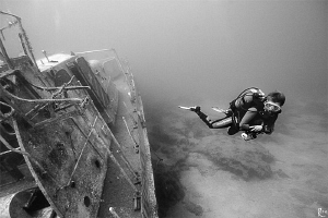 Female diver explores a shipwreck. B/W shot, ambient ligh... by Rico Besserdich 